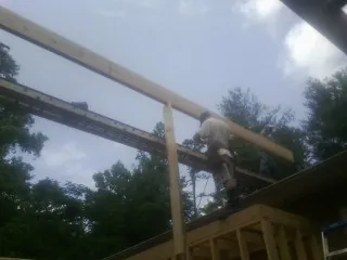 Carpenter setting a ridge beam over a new addition frame — Ice Dam Removal by Roofing Brothers in Carbon