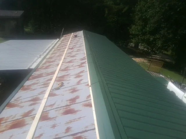 Old rusted panels beside newly installed green metal roofing — Wind Damage Roof Repair by Roofing Brothers in Carbon