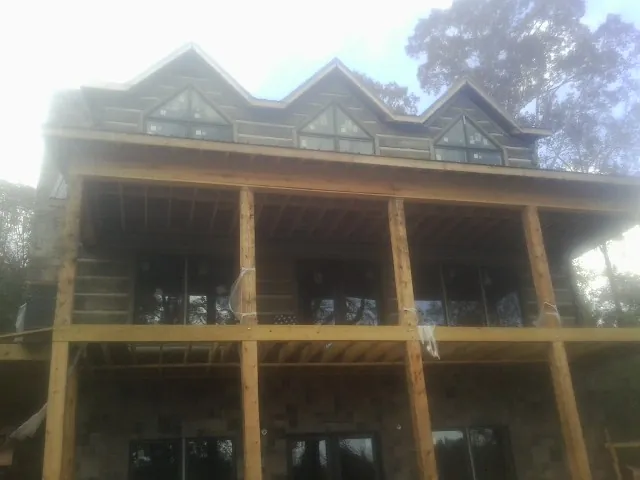 Dormers and porch framing on a large log home under construction — Roof Coating work by our crew in Carbon