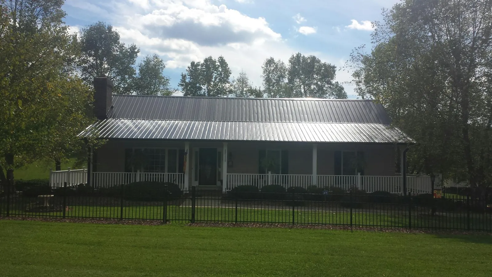 Gray metal roof on a brick ranch with a full width front porch — Gutter Guard Installation work by our crew in Carbon