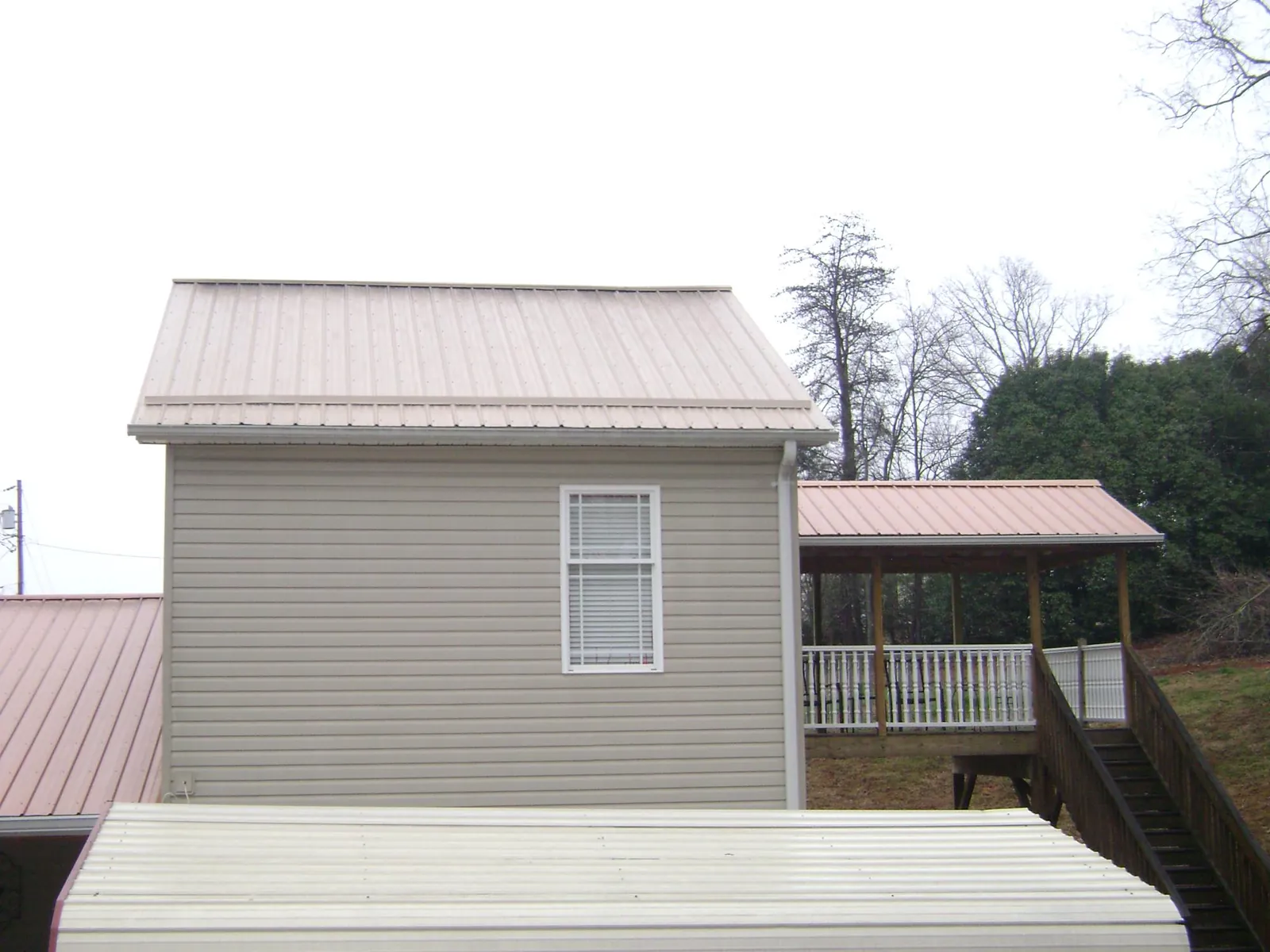 Tan metal roofs on a two story addition and attached porch, from a Roof Replacement job in Carbon