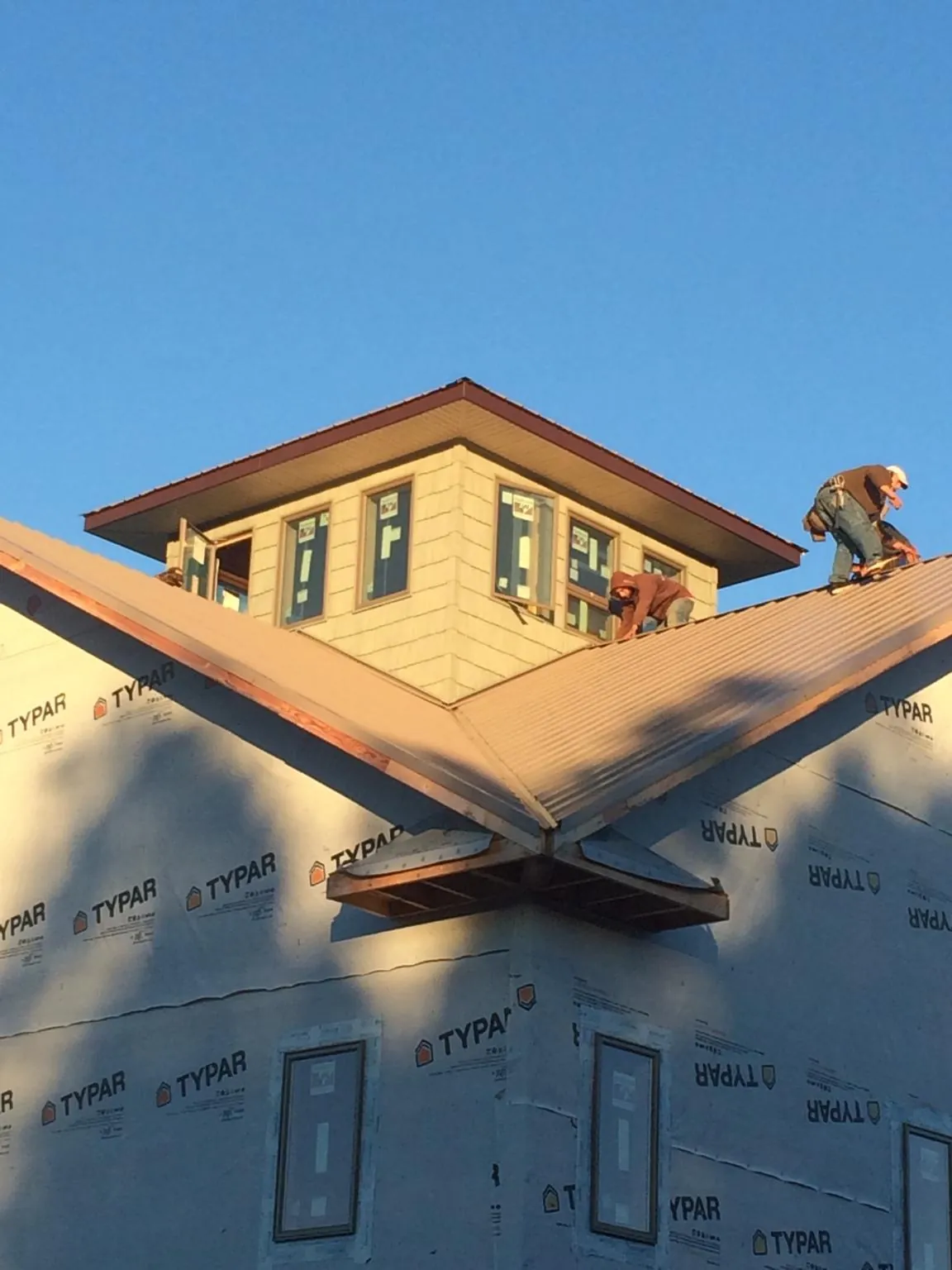 Roofers working around a rooftop cupola on a new metal roof at sunset — Roof Waterproofing in Carbon by Roofing Brothers